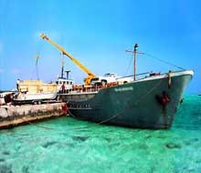 Topsider home components being unloaded from a small vessel at a remote tropical island port.