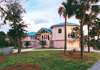 Coastal island luxury home on pilings/stilts with metal roof and stucco exterior built on Tybee Island, Georgia.