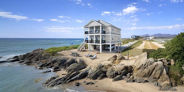 Two-story Topsider home elevated on pilings at a rocky coastal site