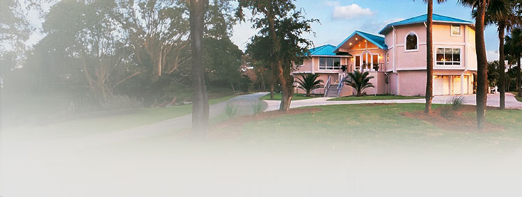 Coastal South Carolina hurricane-resistant home elevated on concrete piers with flood vents and enclosed ground level, featuring octagon design and palm trees at dusk