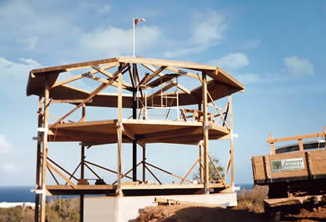 Topsider Home Under Construction on Water Island, US Virgin Islands | Post & Beam with Cistern Foundation Topsider post and beam home under construction on Water Island, US Virgin Islands, showing timber frame structure elevated above a concrete cistern for rainwater catchment